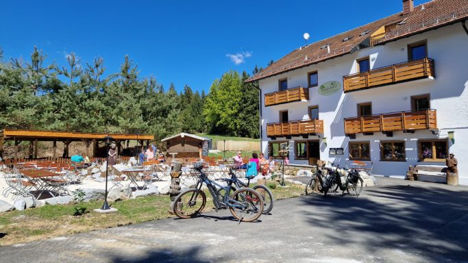 Blick auf ein Gasthaus mit holzverkleideten Balkonen und Fahrrädern im Vordergrund.