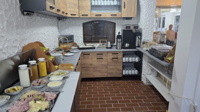 Küche mit Holzschränken, Zubereitung von Speisen und verschiedenen Zutaten auf der Arbeitsplatte.